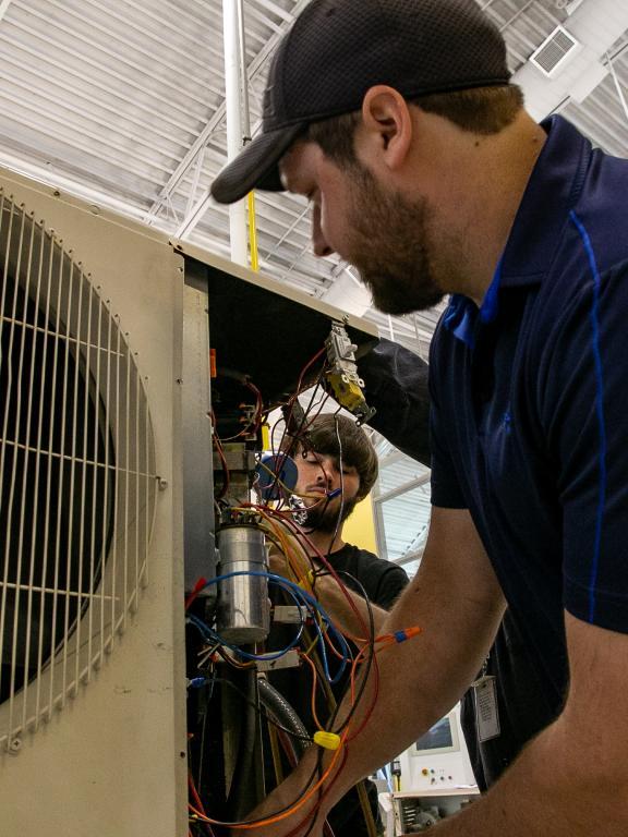 HVAC students work on an air conditioning unit