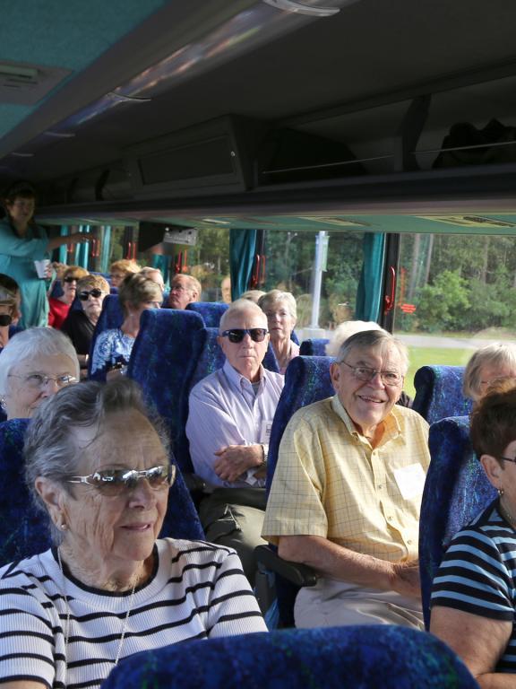 Group of older adults sit in a tour bus