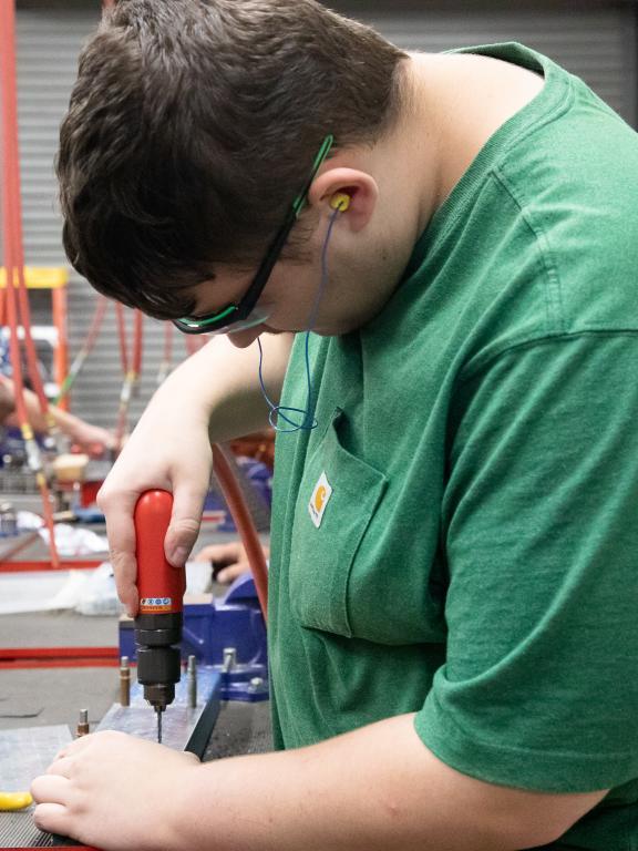 Student in the Advanced Aviation Sheet Metal class uses a drill