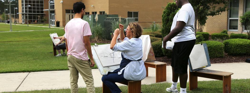 Art instructor at easel with two students